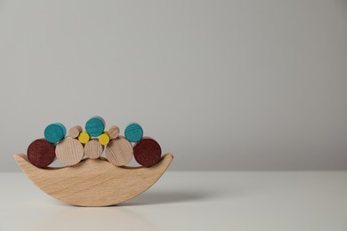 Photo of Wooden balance toy on white table near light grey wall, space for text. Children's development