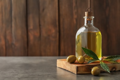 Photo of Wooden board with olives and fresh oil on table