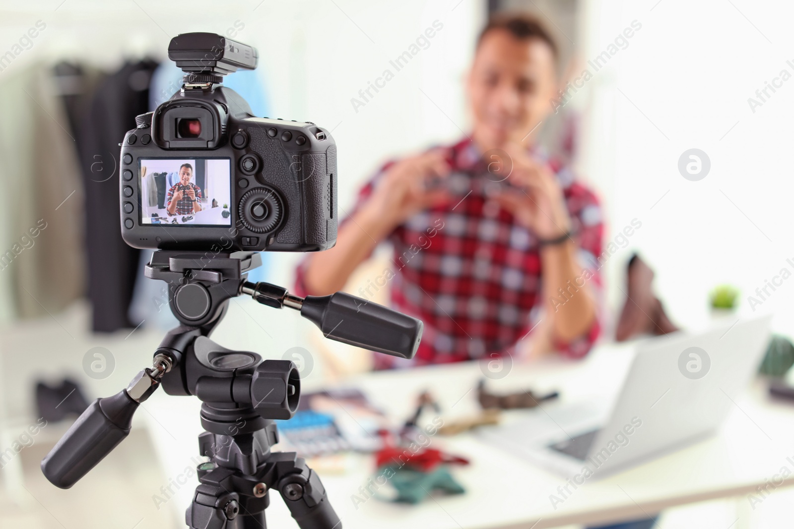 Photo of Fashion blogger recording video indoors, focus on camera display. Space for text