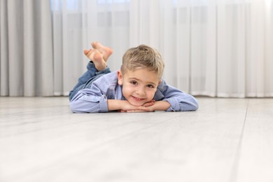 Photo of Cute little boy lying on warm floor at home. Heating system