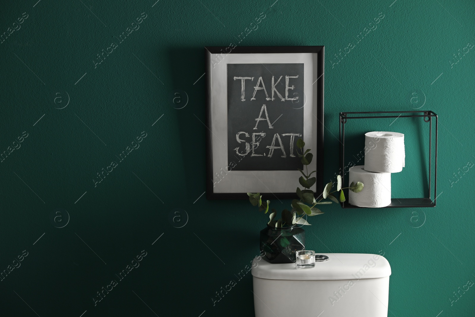 Photo of Decor elements, paper rolls and toilet bowl near green wall, space for text. Bathroom interior