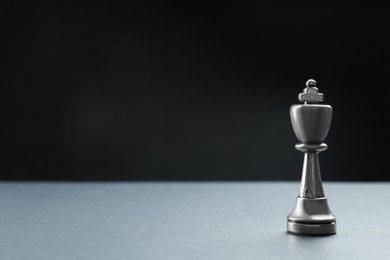 Photo of Metal king on table against dark background, space for text. Chess piece
