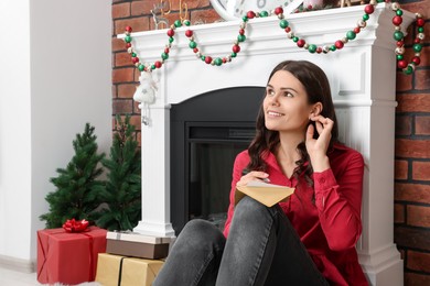 Photo of Young woman writing message in greeting card indoors