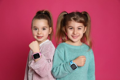 Photo of Little girls with smart watches on pink background