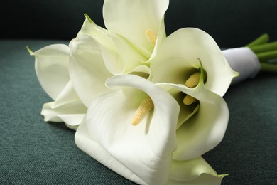 Photo of Beautiful calla lily flowers on sofa, closeup