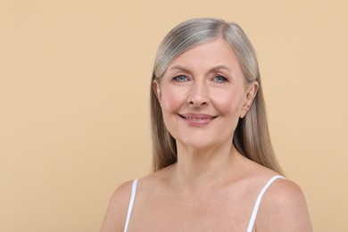 Photo of Portrait of beautiful senior woman on beige background. Space for text