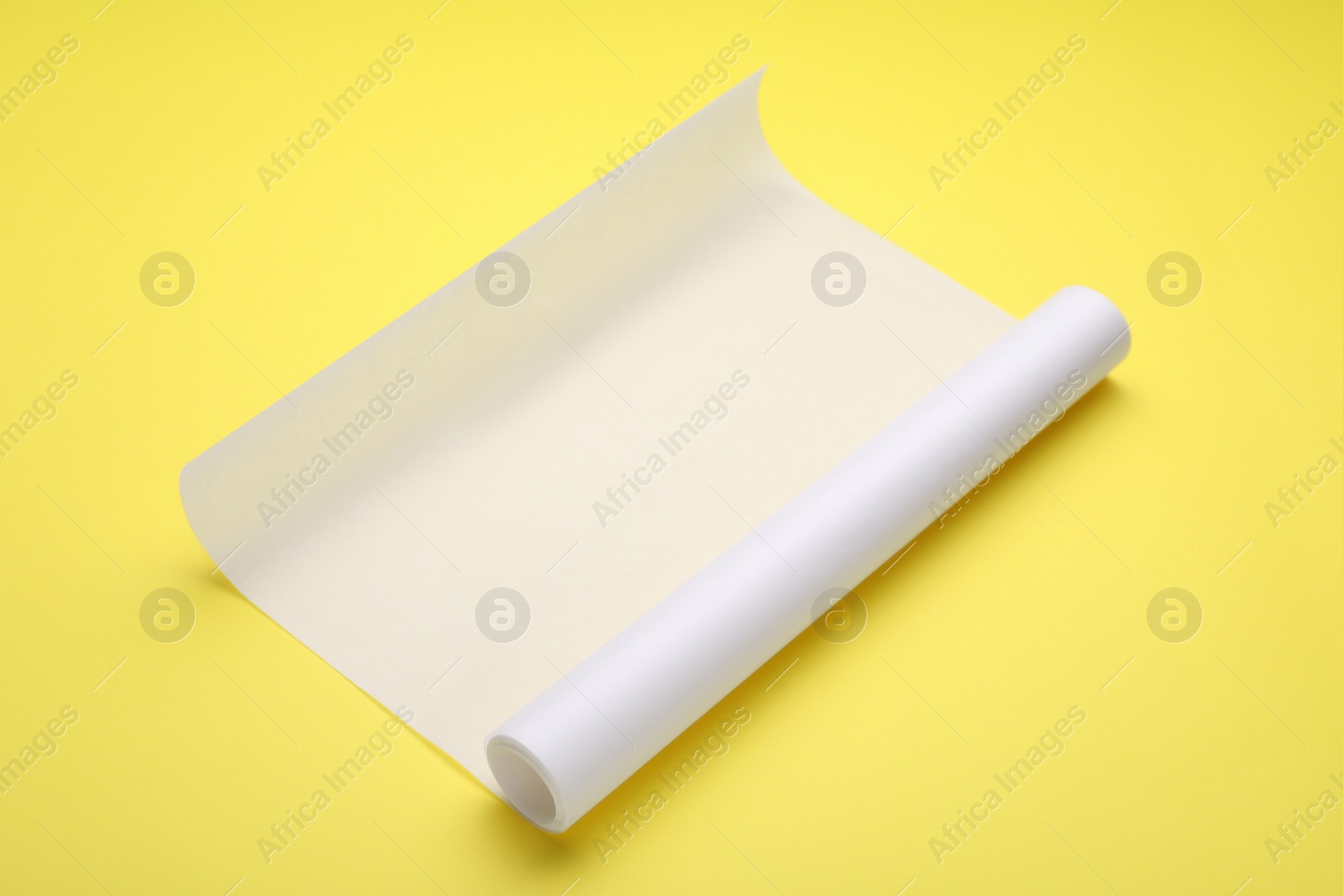 Photo of Roll of baking paper on yellow background