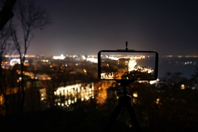 Taking photo of beautiful cityscape at night with smartphone mounted on tripod