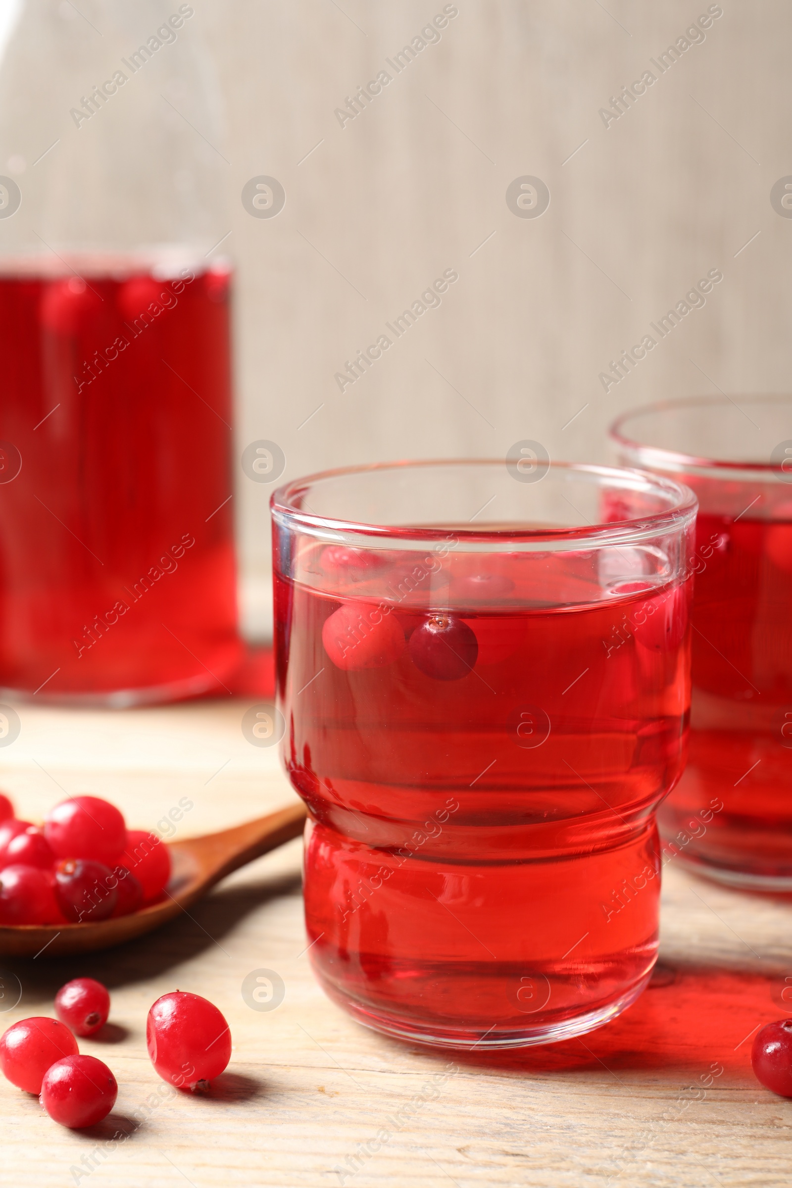 Photo of Tasty cranberry juice in glasses and fresh berries on wooden table, closeup