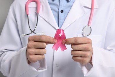 Photo of Mammologist with pink ribbon on light grey background, closeup. Breast cancer awareness