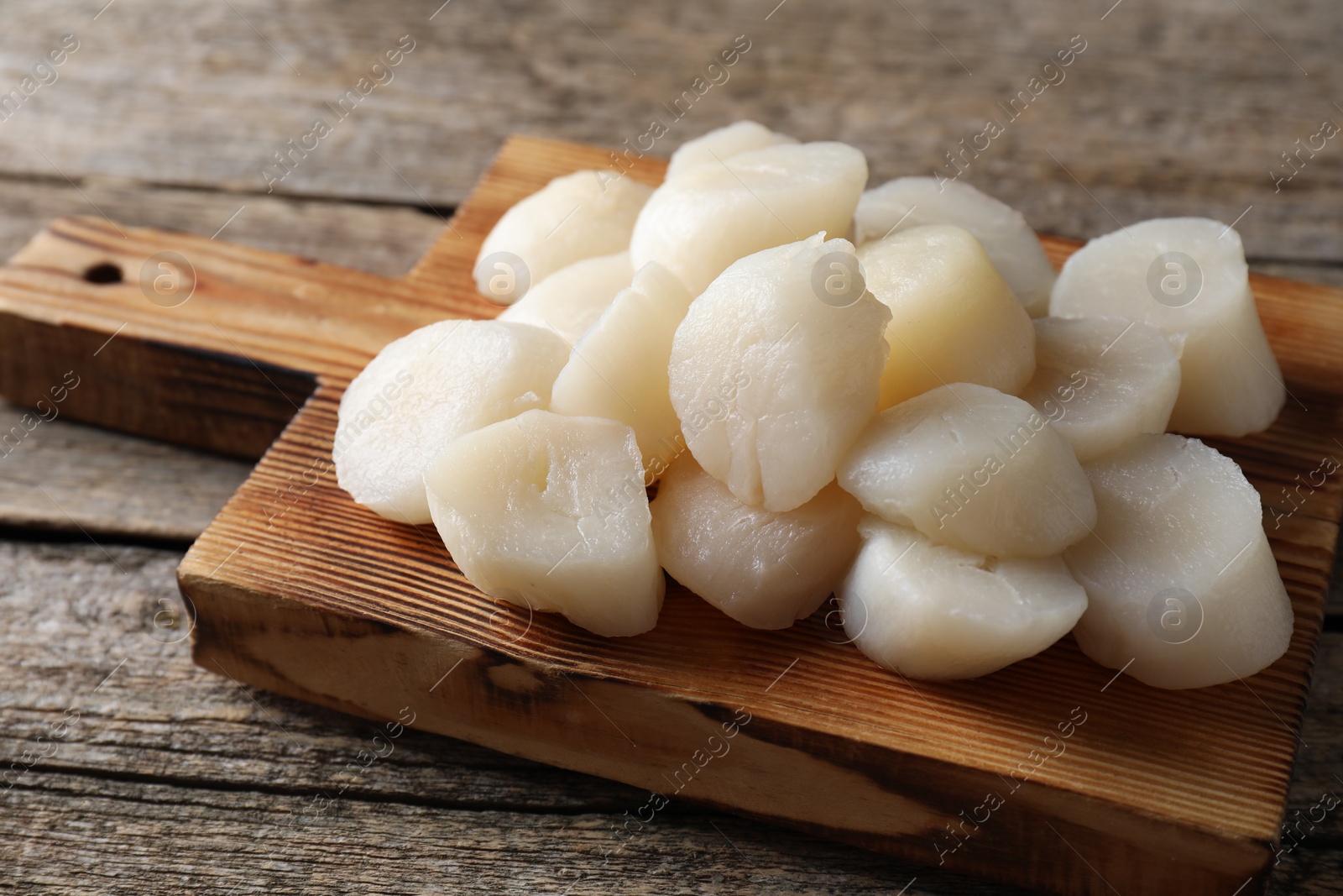 Photo of Fresh raw scallops on wooden table, closeup