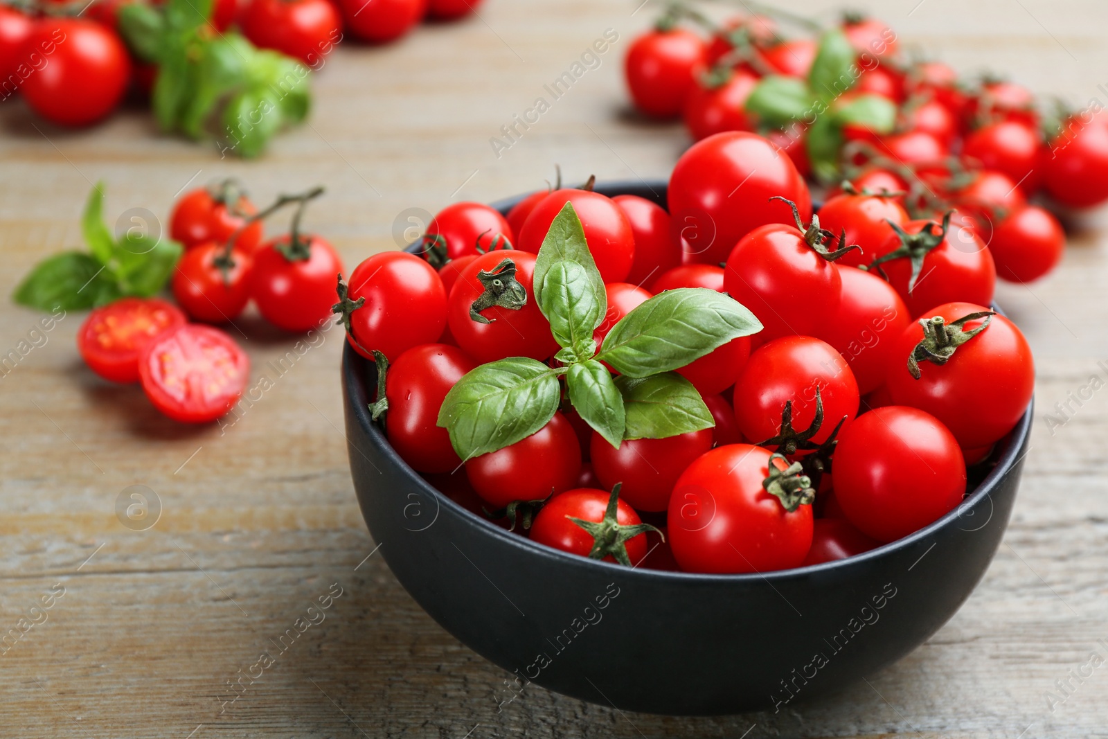 Photo of Fresh cherry tomatoes and basil leaves on wooden table