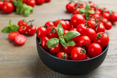 Fresh cherry tomatoes and basil leaves on wooden table