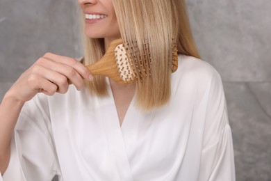 Woman in white robe brushing her hair indoors, closeup