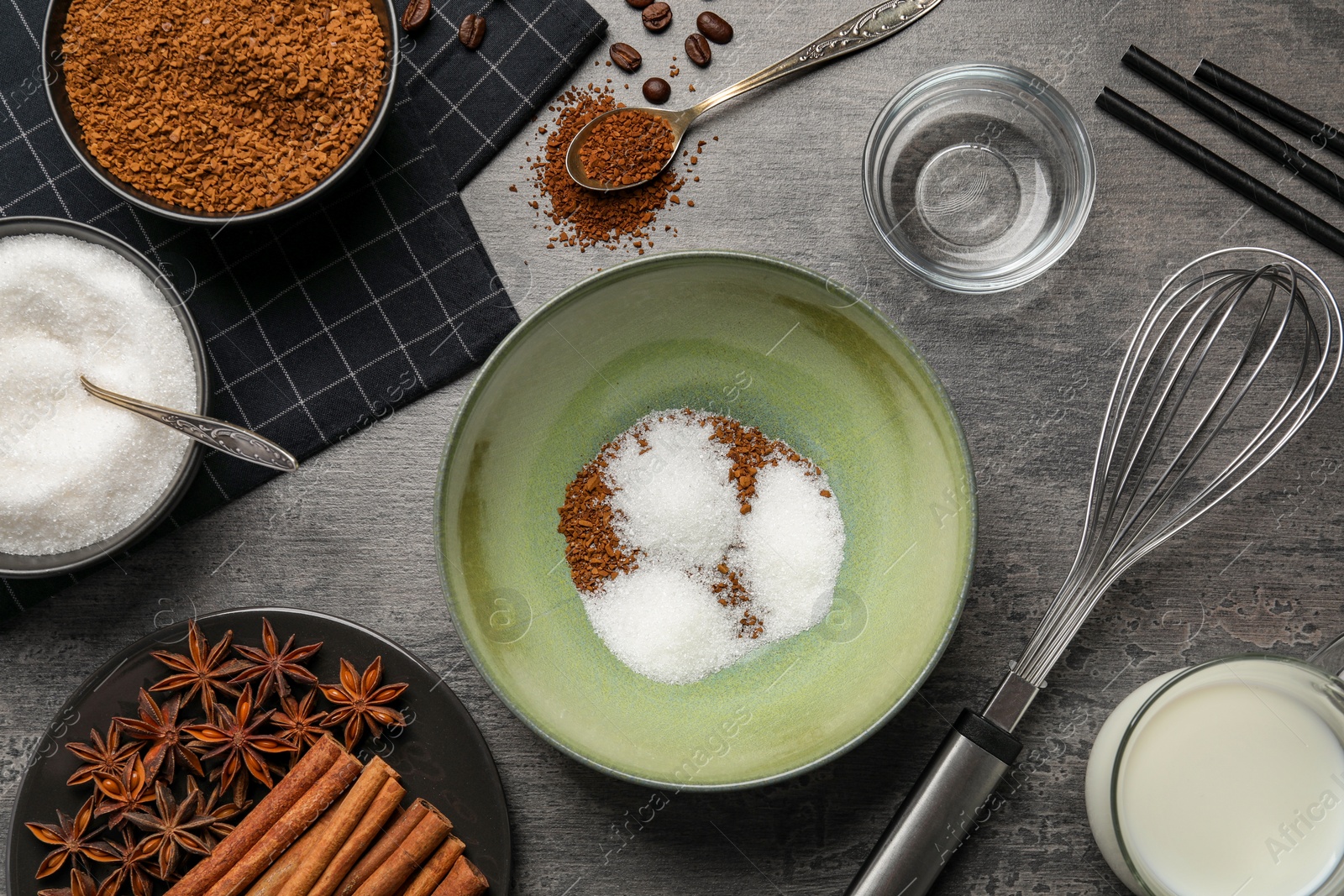 Photo of Making dalgona coffee. Instant granules, sugar, cinnamon sticks, milk and whisk on table, flat lay