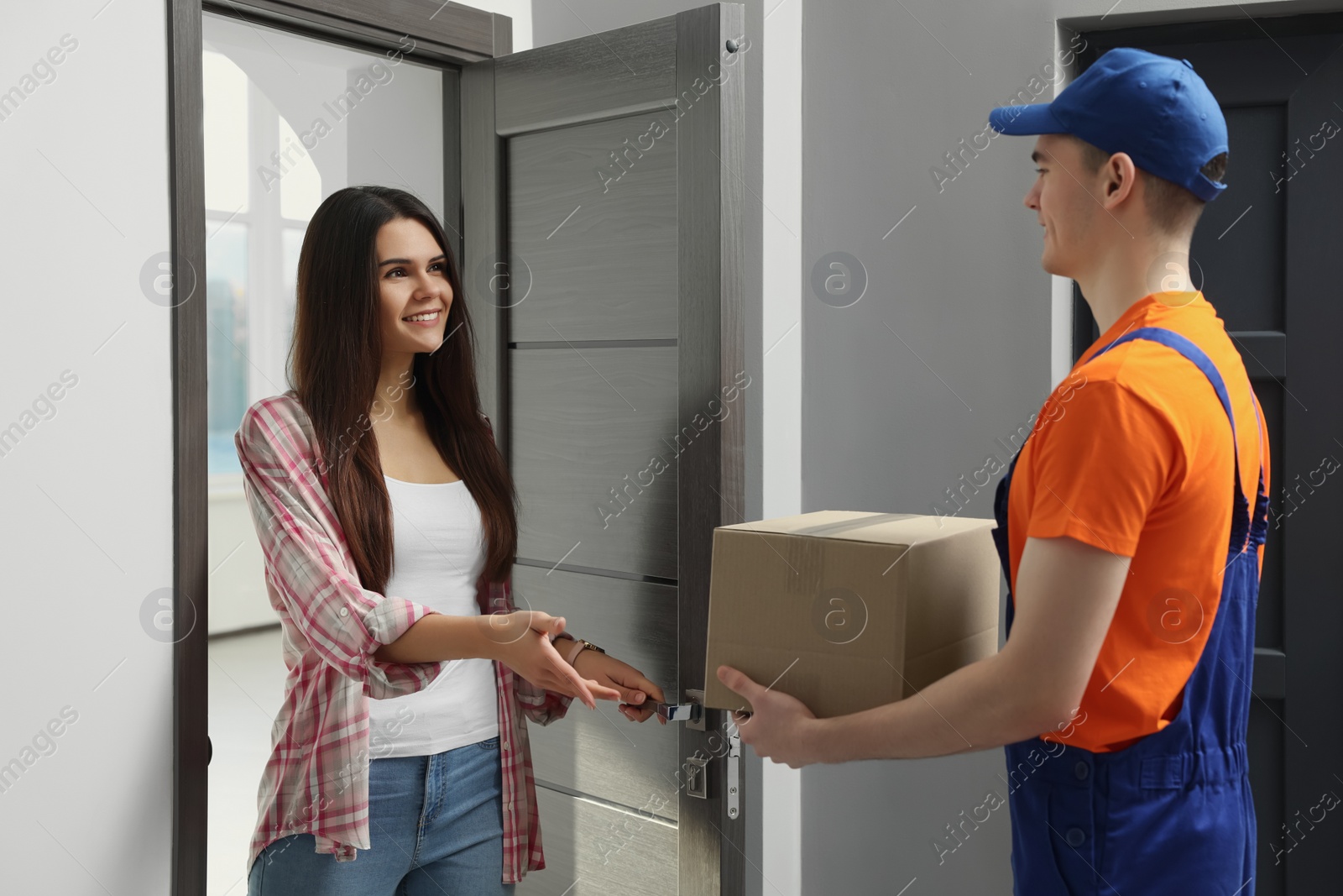 Photo of Woman receiving parcel from courier at home