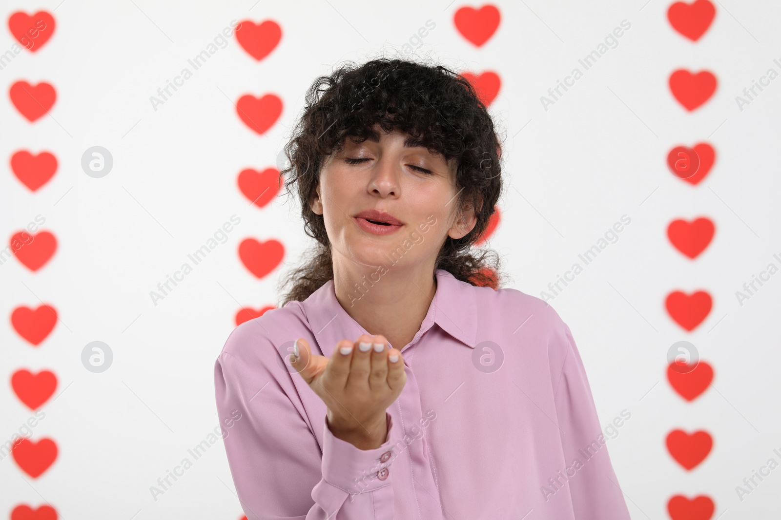 Photo of Happy young woman blowing kiss into camera on decorated background