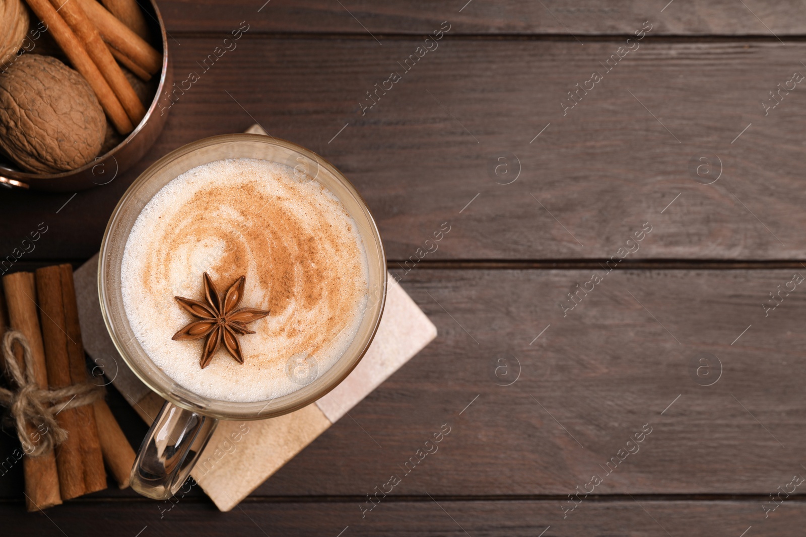 Photo of Delicious eggnog with spices on wooden table, flat lay. Space for text