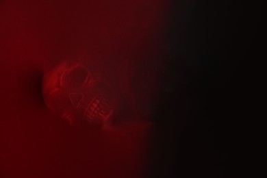 Photo of Silhouette of creepy ghost with skull behind red cloth. Space for text