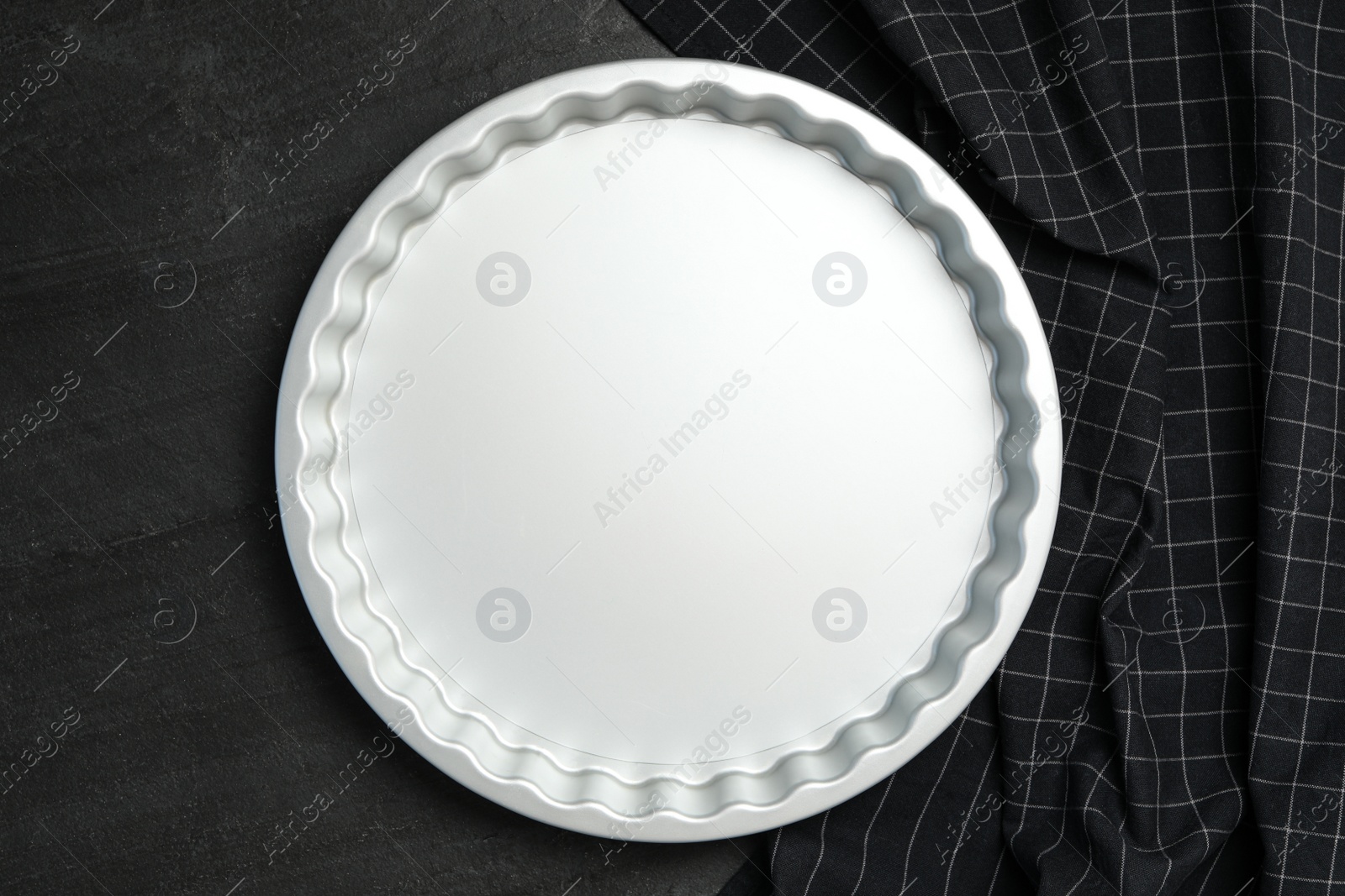 Photo of Baking dish and tablecloth on black table, flat lay. Cooking utensil