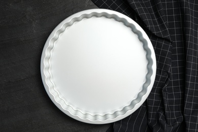 Photo of Baking dish and tablecloth on black table, flat lay. Cooking utensil