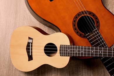 Ukulele and acoustic guitar on wooden background, flat lay. String musical instruments