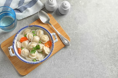 Photo of Bowl of dumplings in broth served on table, top view. Space for text