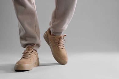 Man walking in sneakers on light grey background, closeup. Space for text