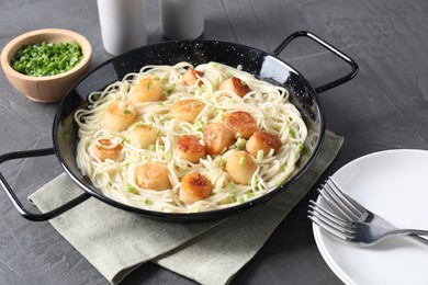 Photo of Delicious scallop pasta with green onion served on grey table