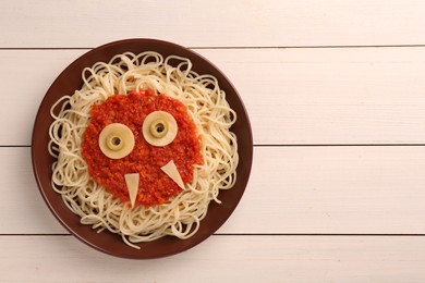 Plate with funny monster made of tasty pasta on white wooden table, top view with space for text. Halloween food