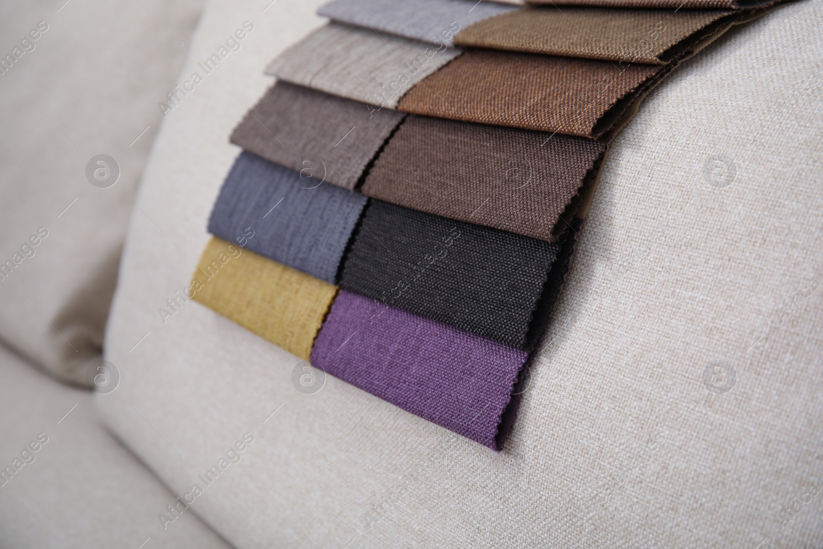 Photo of Catalog of colorful fabric samples on beige sofa, closeup