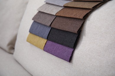 Photo of Catalog of colorful fabric samples on beige sofa, closeup