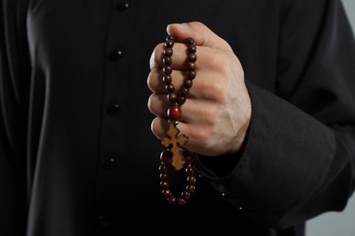Photo of Priest in cassock with rosary beads, closeup