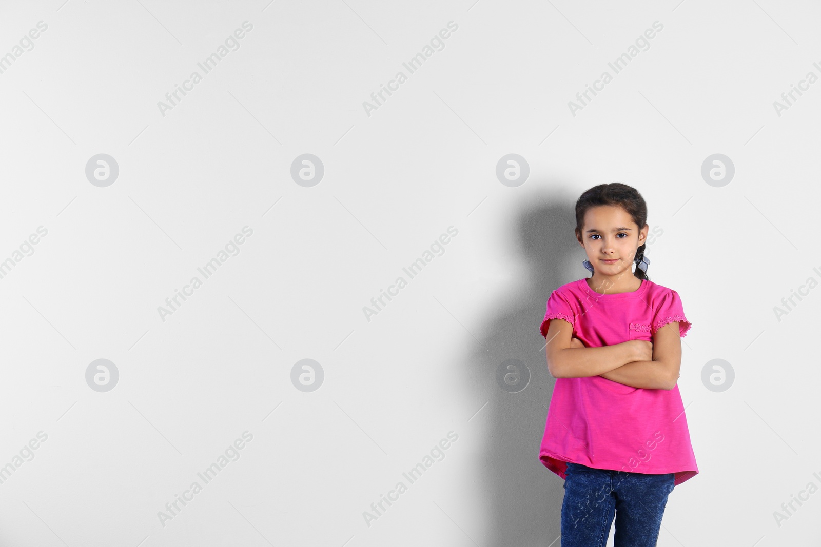 Photo of Portrait of cute little girl on light background, space for text