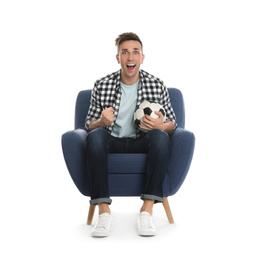 Handsome young man sitting in armchair and watching soccer match on white background