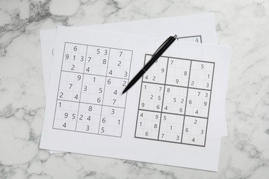 Sudoku and pen on white marble table, top view