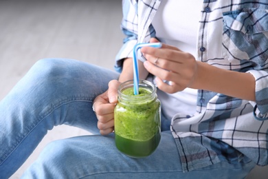 Young woman with mason jar of healthy smoothie, closeup