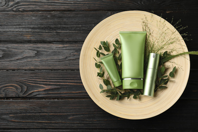 Photo of Set of cosmetic products and plants on dark wooden table, top view. Space for text