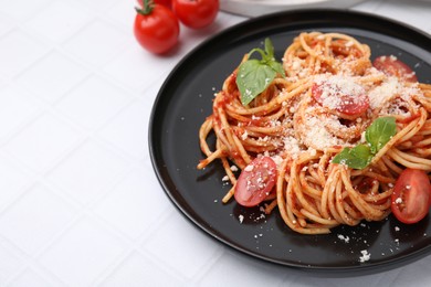 Tasty pasta with tomato sauce, cheese and basil on white tiled table, space for text