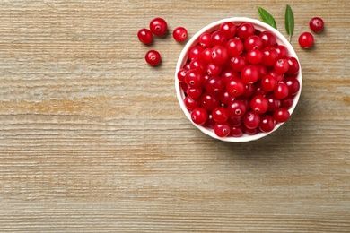 Photo of Tasty ripe cranberries on wooden table, flat lay. Space for text