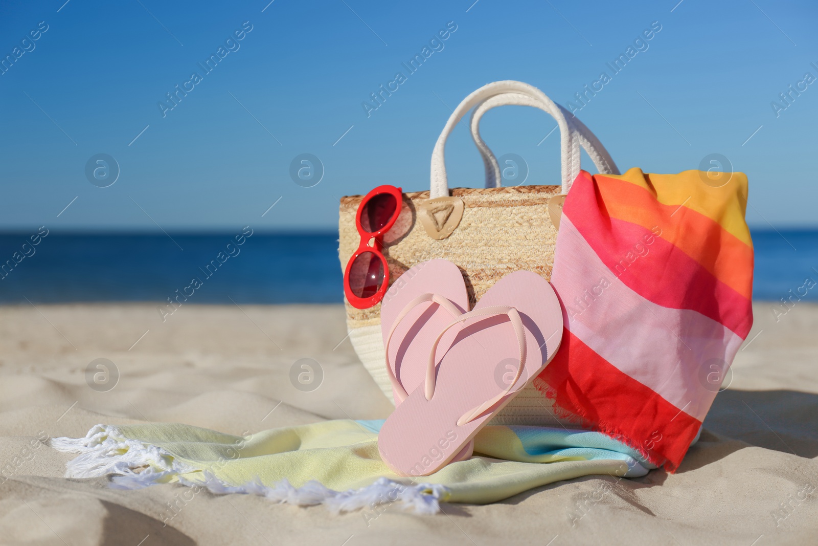 Photo of Stylish beach accessories for summer vacation on sand near sea. Space for text