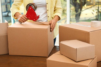 Woman packing box indoors, closeup. Moving day