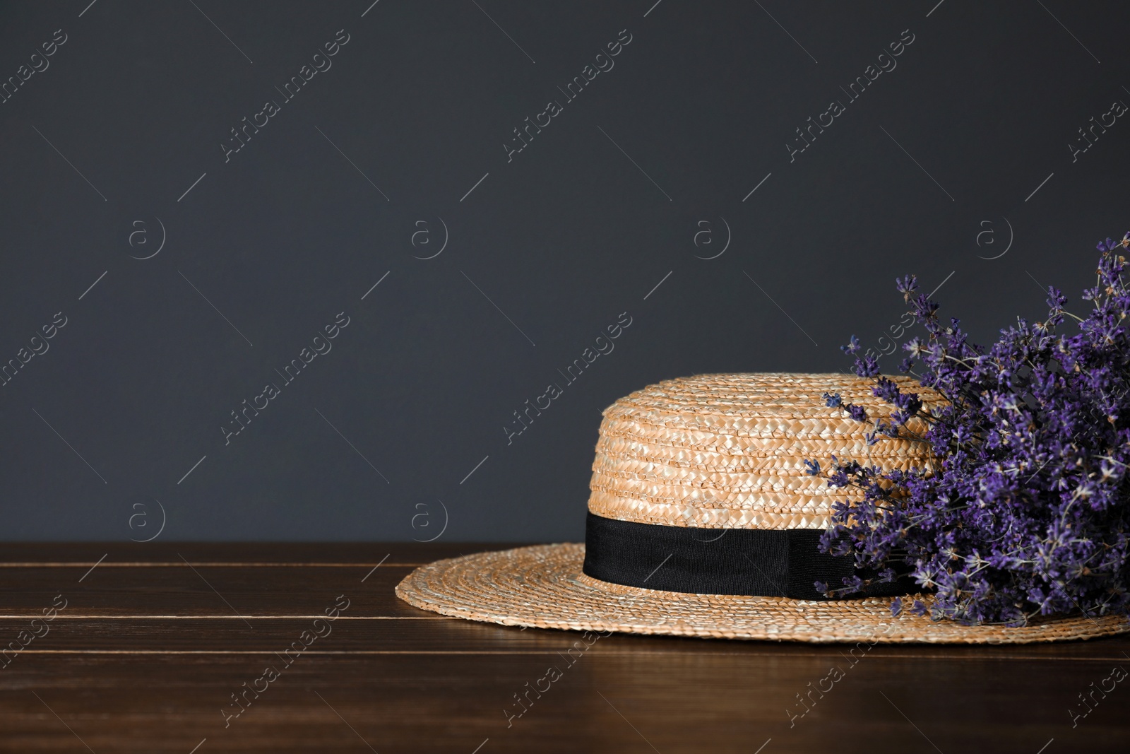 Photo of Straw hat and flowers on wooden table. Space for text