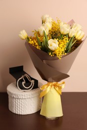 Photo of Bouquet with beautiful spring flowers and necklace on wooden table