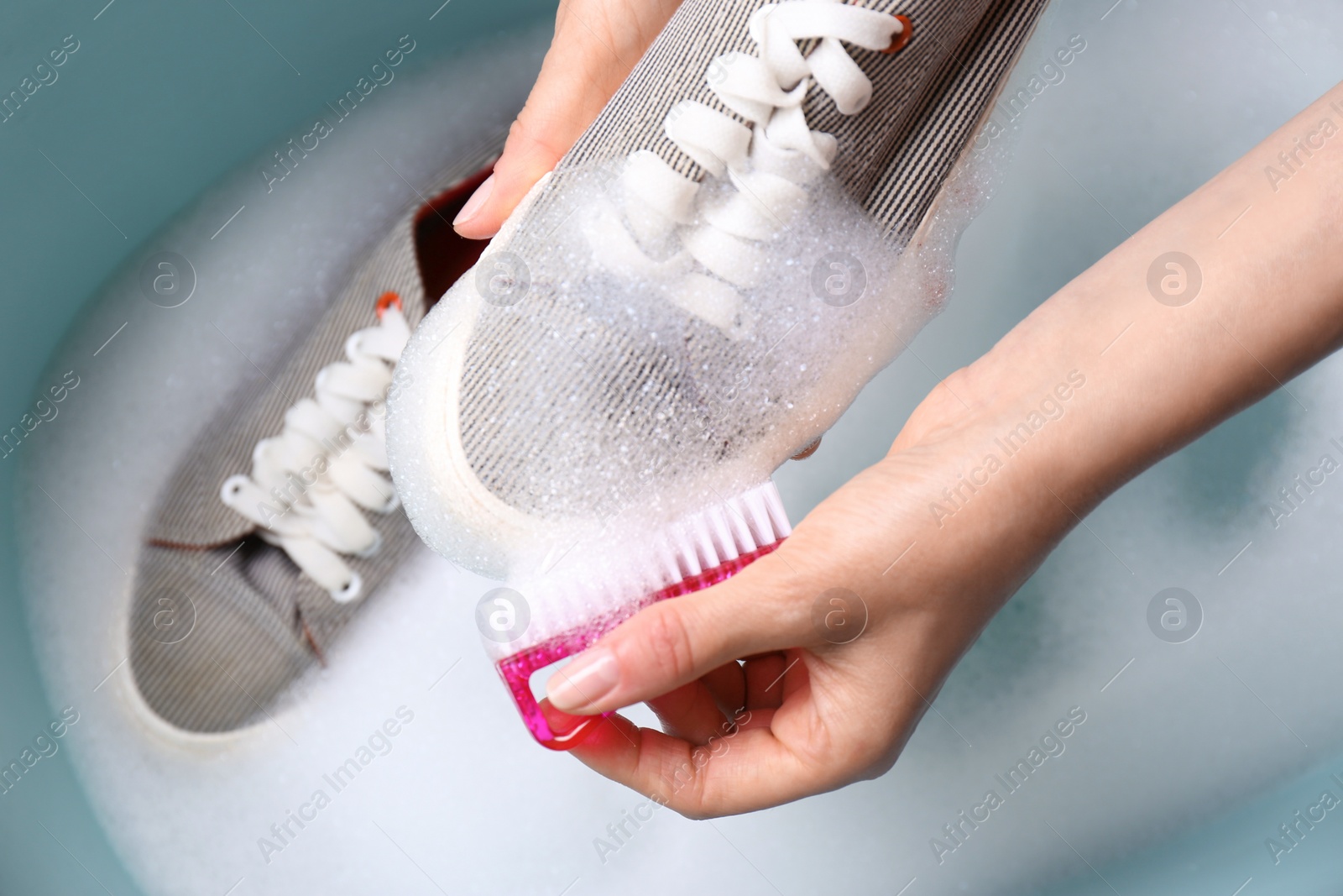 Photo of Woman washing shoe with brush in basin, closeup