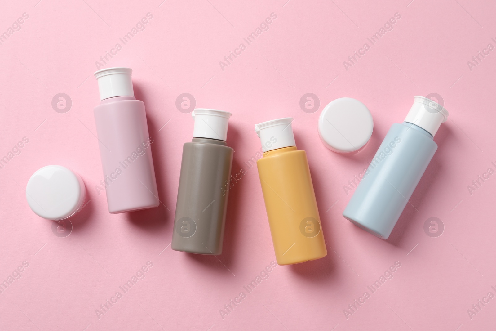 Photo of Cosmetic travel kit on pink background, flat lay. Bath accessories