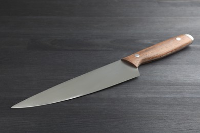 Photo of One sharp knife on black wooden table, closeup