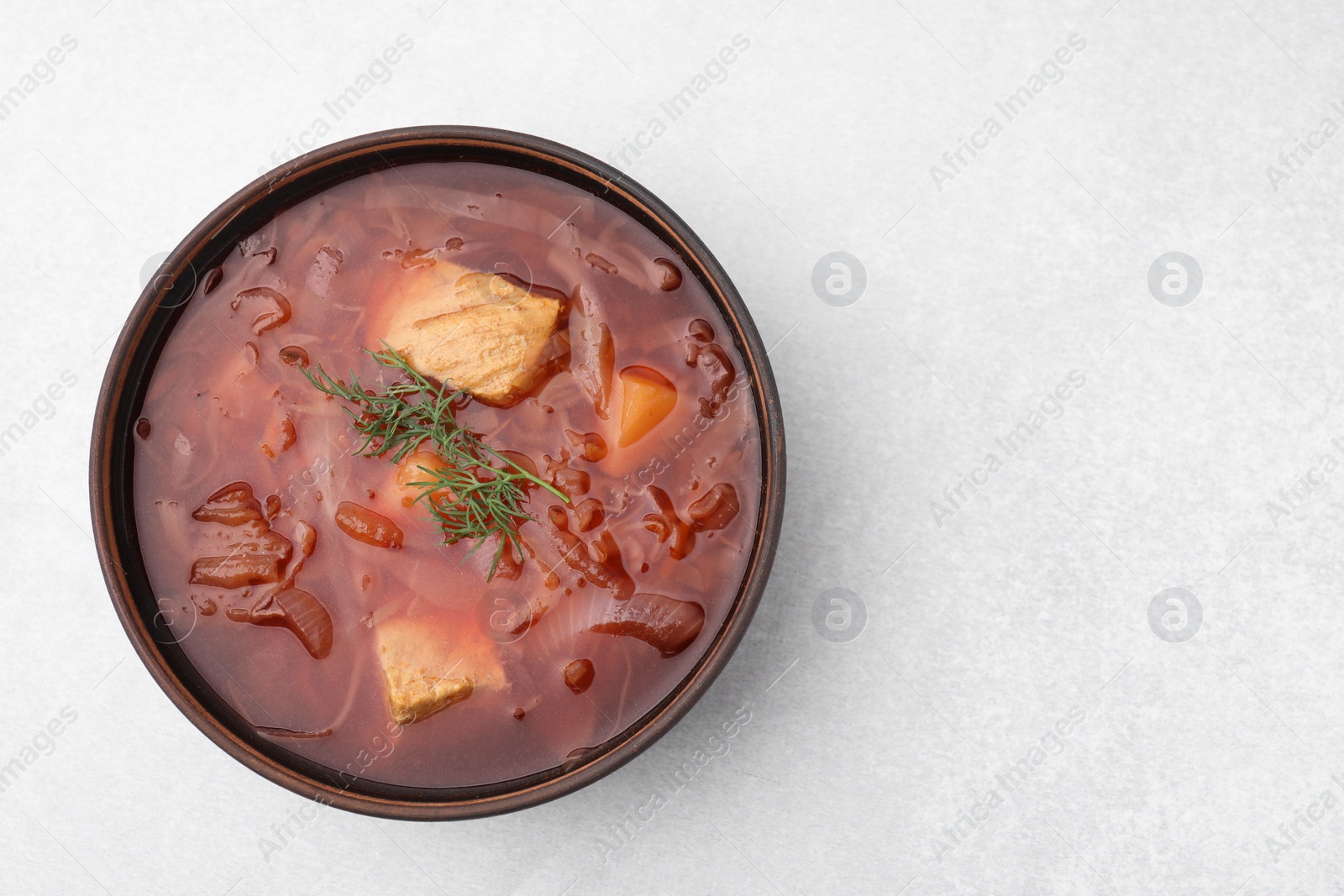 Photo of Bowl of delicious borscht on white table., top view. Space for text