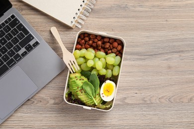 Photo of Healthy products high in vegetable fats near laptop on wooden table, flat lay. Space for text