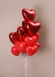 Photo of Bunch of heart shaped balloons on beige background. Valentine's day celebration